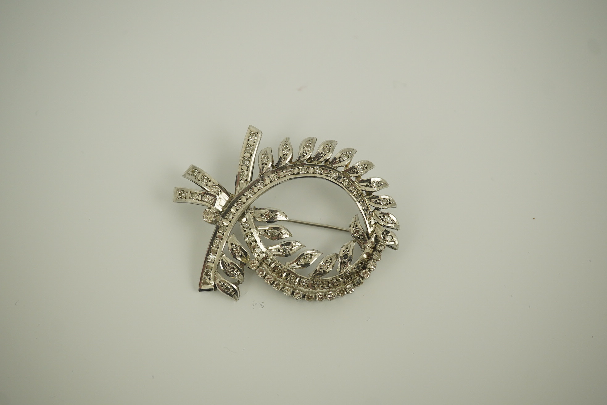 A recent white gold and diamond cluster set scrolling wreath brooch